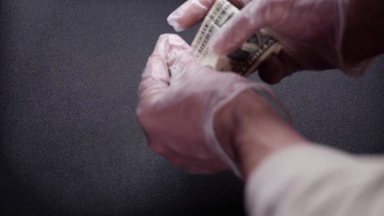 A single banknote of one dollar. Handed out by a man with medical gloves. Corona crisis.