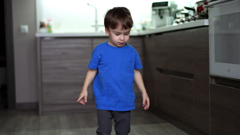 two-year old toddler playing with apples on the floor. child stands up and steps away from fruit.