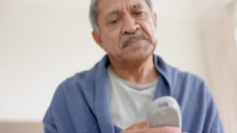 Biracial-senior-man-testing-blood-at-home,-slow-motion