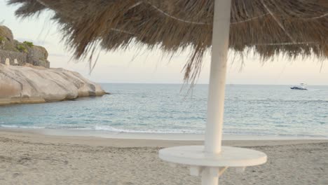 Straw-umbrella-and-tropical-coastline-of-Tenerife,-handheld-view