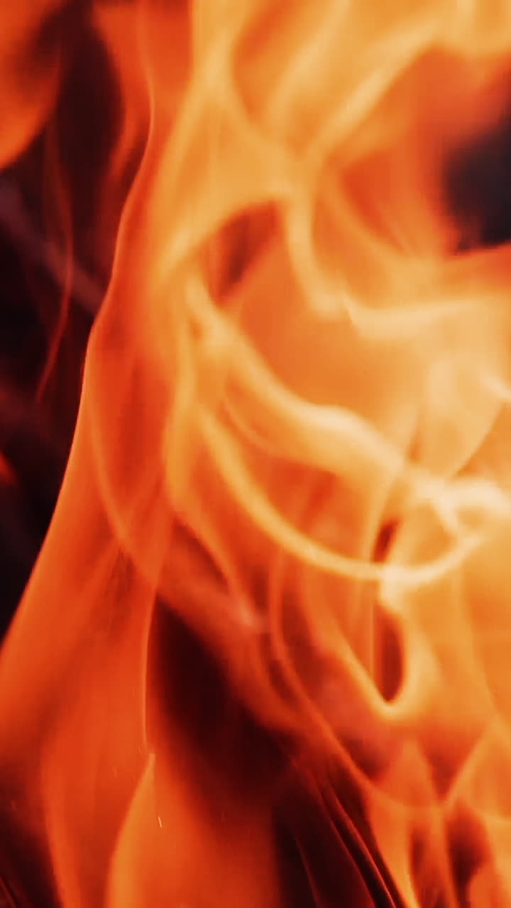 Slow motion of fire flame. Beautiful fire burns brightly. Burning logs in orange flame. Close-up. Vertical video