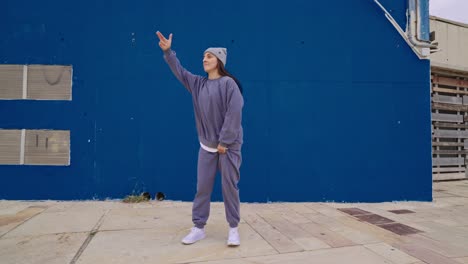 a woman dancing in front of a blue wall