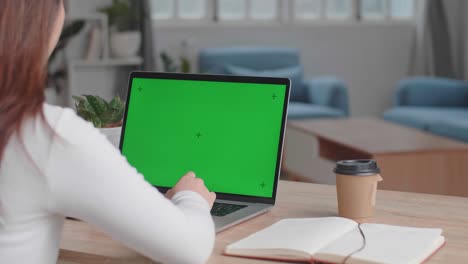 niña escribiendo en el teclado de la computadora de una computadora portátil con pantalla verde en casa