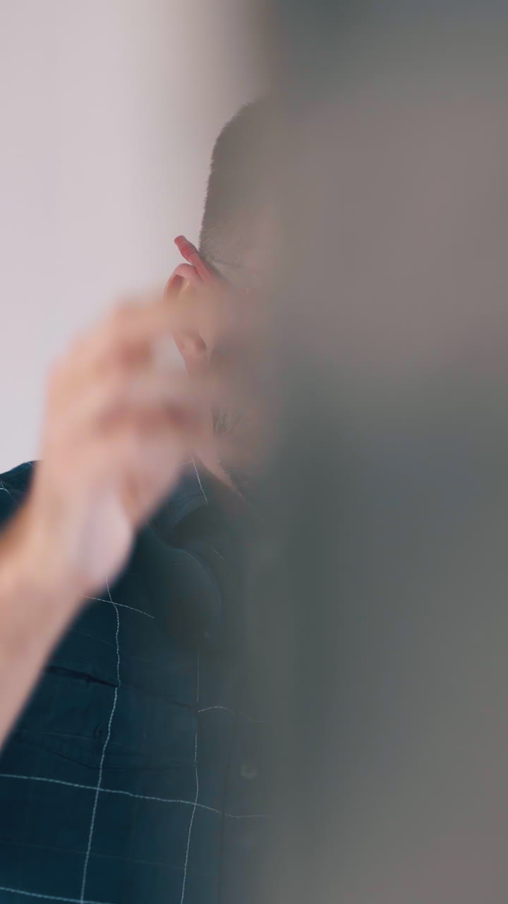 Dolly cam shot: young man in goggle and checkered shirt uses modern long level to check wall at spacious light room renewal