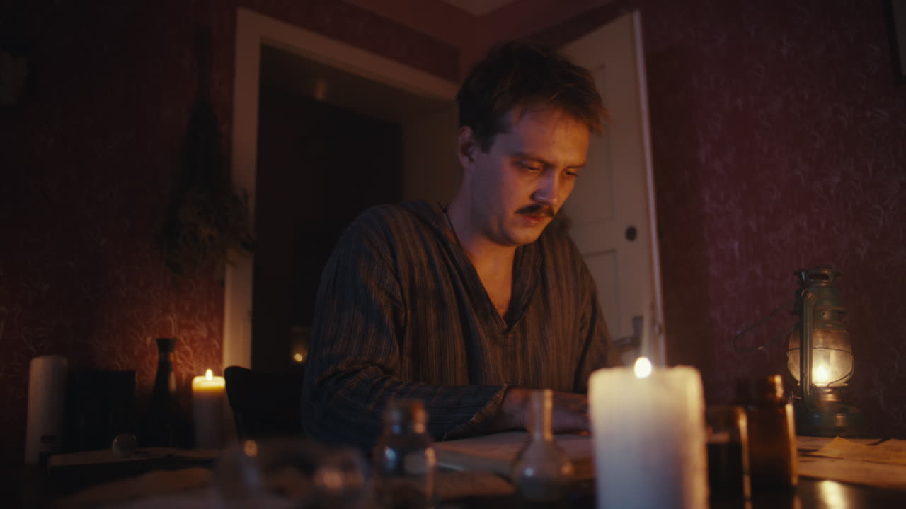 A man studying or working in a dimly lit room by candlelight