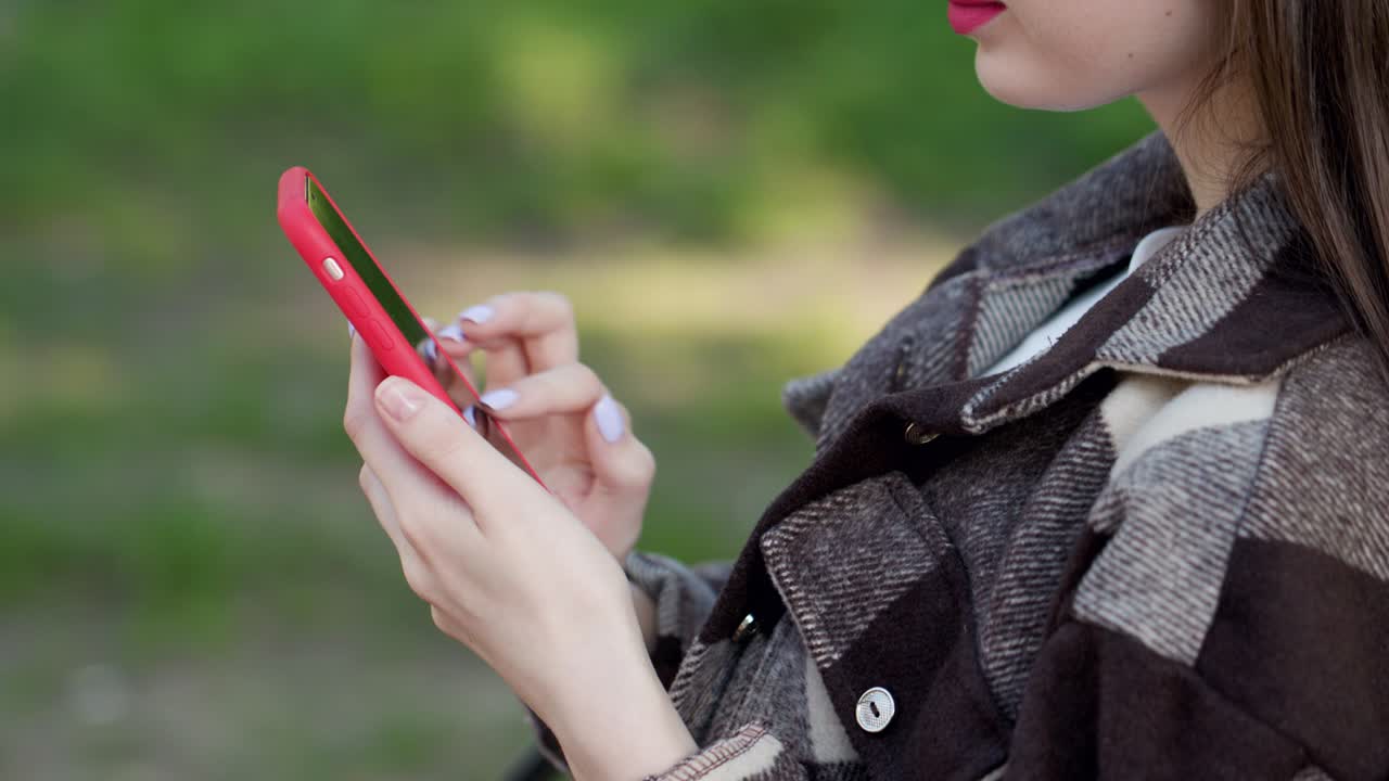 봄이나 여름에 공원에서 스마트폰을 사용하는 어린 소녀, 스마트폰을 사용하는 인터넷, 클로즈업 패션 모델, 인스타그램, 페이스북 컨셉에 게시물, 공원에서 드폰을 사용하는 소녀