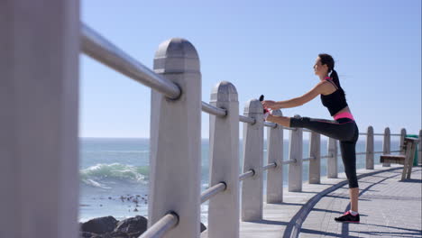 mujer atlética estirándose en el paseo marítimo antes de correr