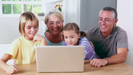 -Bruder-Und-Schwester-Schauen-Mit-Großeltern-Auf-Den-Laptop