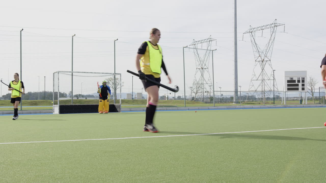 Female hockey players practicing on field, focusing on teamwork and strategy