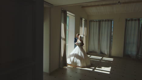 The-Bride-And-Groom-In-Elegant-Dresses-Standing-At-A-Window-In-The-Great-Hall