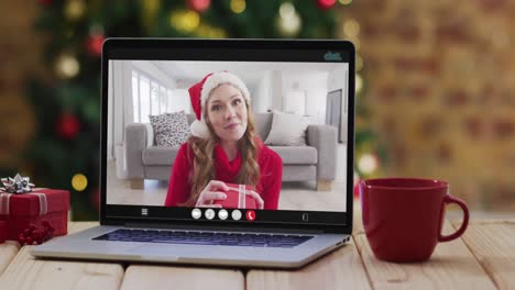 Caucasian-woman-in-santa-costume-on-video-call-on-laptop,-with-smartphone,-tablet-and-decorations