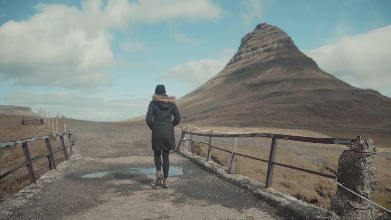Donna che cammina verso la maestosa montagna Kirkjufell in Islanda