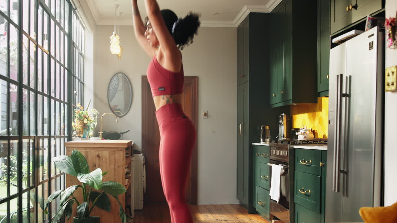 Donna energica che esegue un esercizio burpee in una casa moderna.