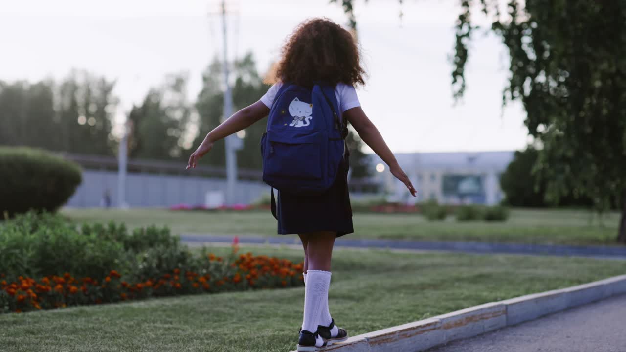 Girl Balancing on Curb with Backpack