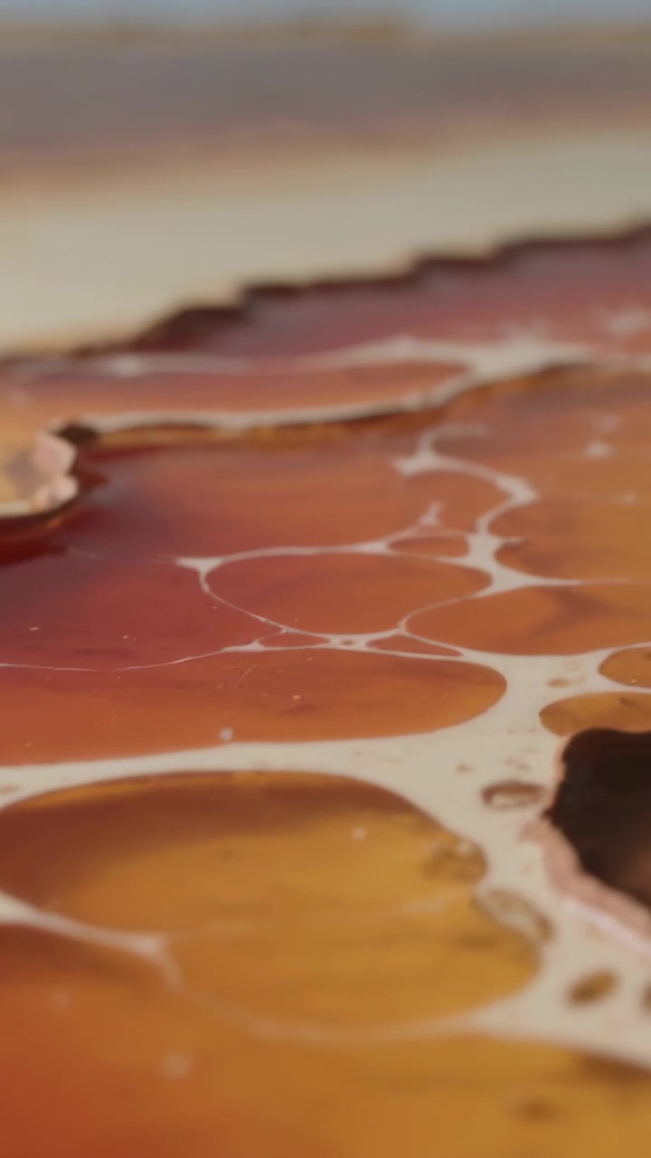 Vertical video: Shifting camera showing poured art on panel, exposing cells and lacing for detail