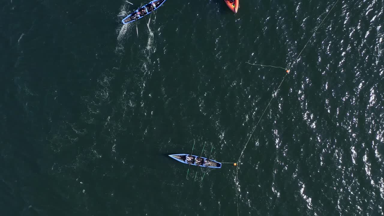 Drone rises to bird's eye view perspective with currach irish canoe boats tethered to buoys in open ocean