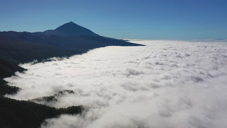 aerial shot of a majestic view from the pico de teide on canary islands of a heavy cloud inversion below the mountains with a clear blue sky above