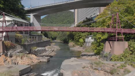 imagen aérea volando bajo un puente sobre un río en jozankei, la famosa ciudad de onsen, hokkaido, japón.