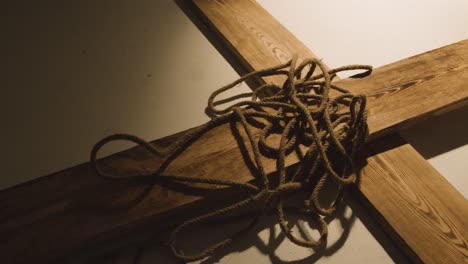 concepto religioso filmado con una cuerda arrojada a una cruz de madera en un charco de luz