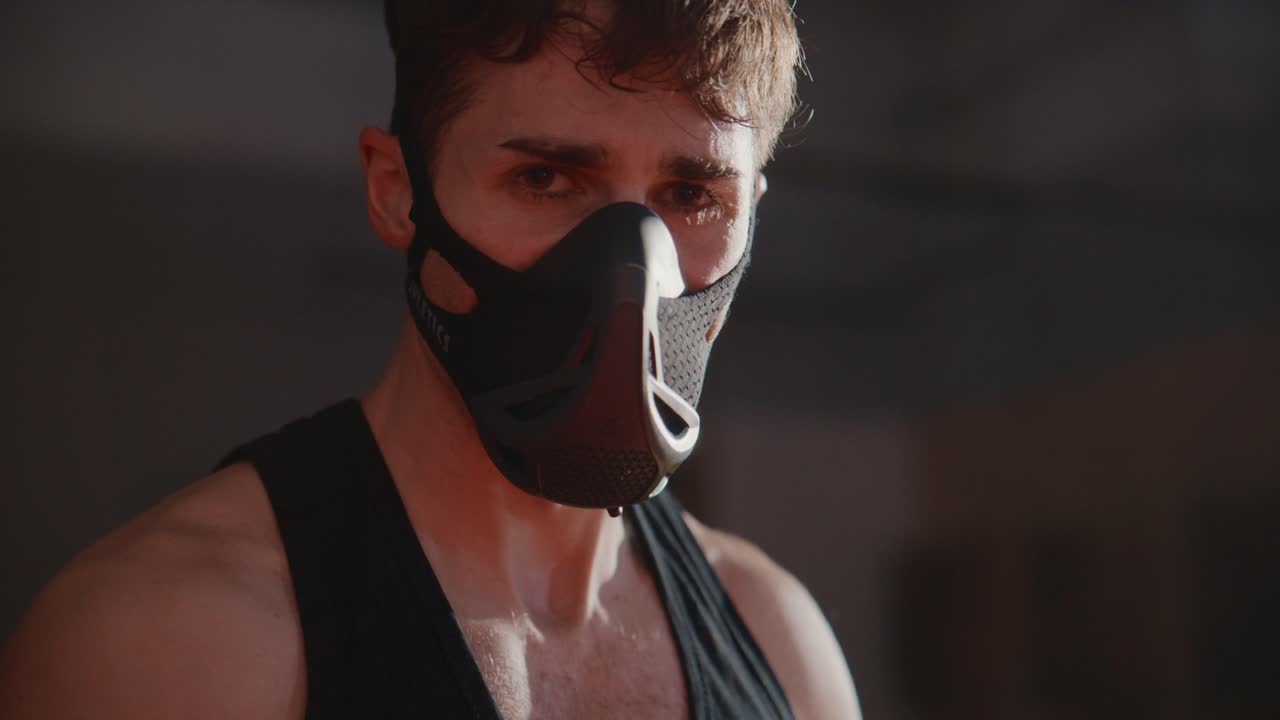 Atleta intenso che indossa una maschera da allenamento e guarda la fotocamera.