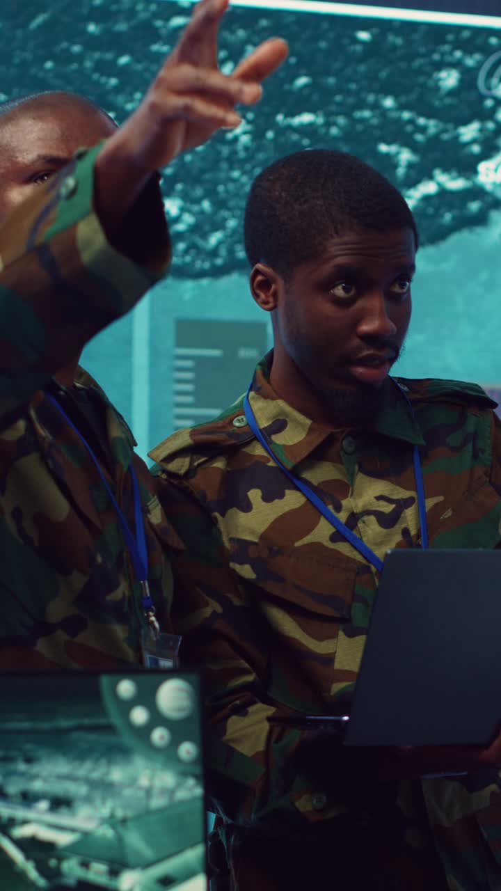 Two Soldiers in Camouflage Uniforms Discussing Data in a Control Room