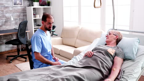 caucasian doctor in nursing home talking with old woman