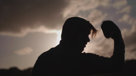 man boxing in park silhouetted by sun in slow motion