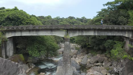 man running across stone bridge through forest on yakushima island, japan