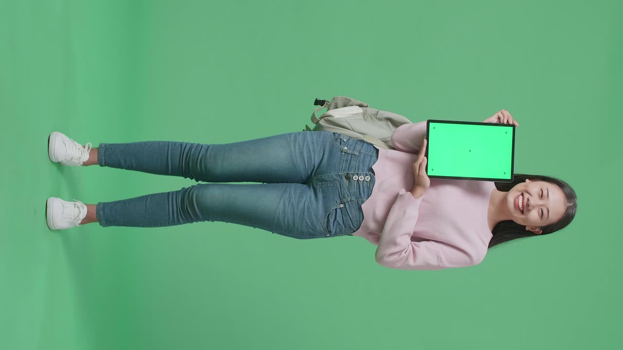cuerpo lleno de estudiante mujer asiática mostrando maquillaje tableta pantalla verde en pantalla verde estudio