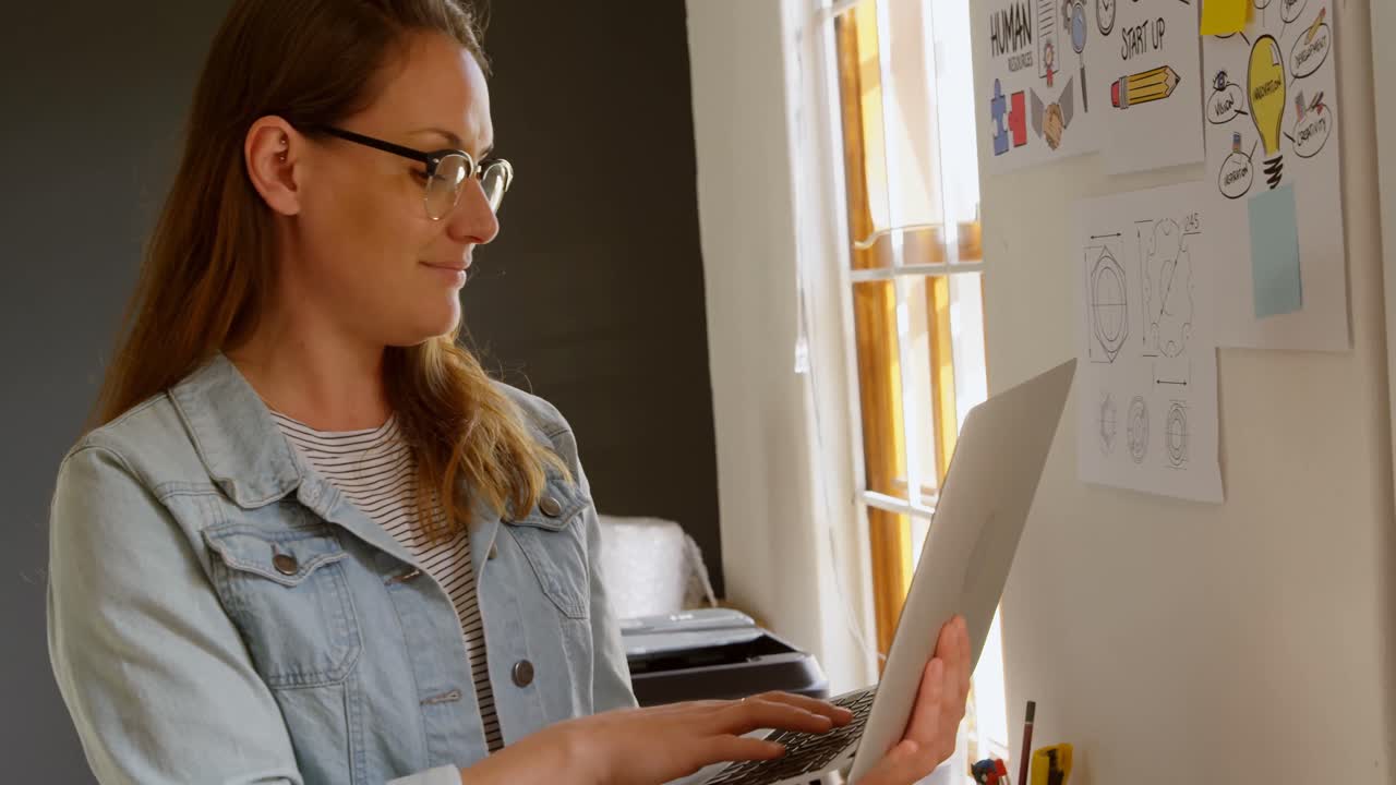 diseñadora de joyas usando una computadora portátil en el taller 4k