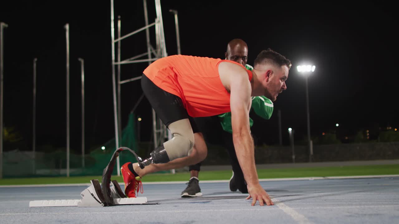 다양한 남성 코치와 장애인 남성 선수가 달리기 블레이드를 가지고 달리기를 시작할 준비가되어 있습니다.