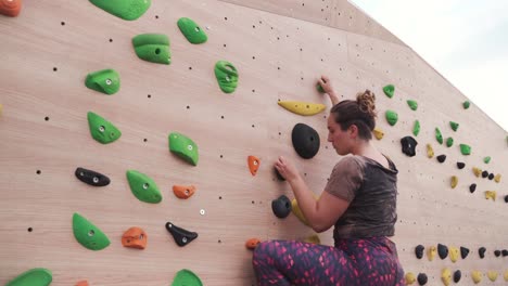 Adult-woman-climbing-on-a-climbing-wall-in-slow-motion,-Cinematic