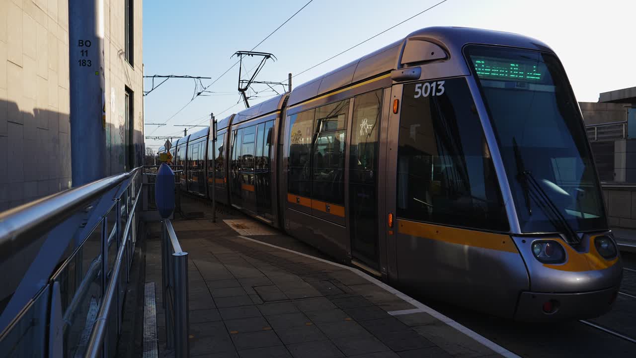 Tram moderno in arrivo e in partenza da una banchina di stazione urbana