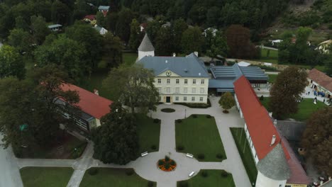 Backwards-Drone-Shot-of-an-old-Mansion-with-a-big-Garden