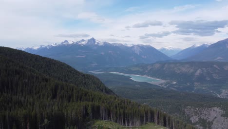 hydroelectric dam in huge mountain landscape with snow trees and bright blue sky with aerial drone panning across in canada bc 4k