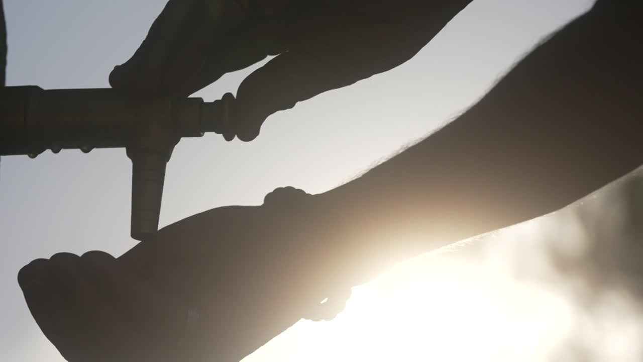 Person washing hands at outdoor water tap