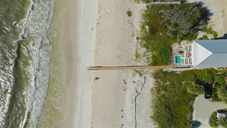 Drone-clip-hovering-over-dock-stretching-across-sandy-beaches-into-water-at-Cape-San-Blas,-Florida