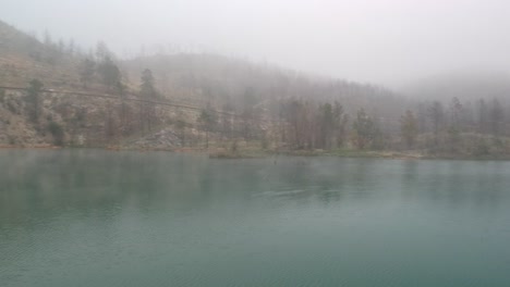 four ducks landing on a lake between mist