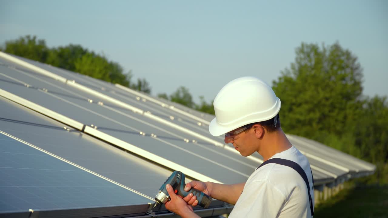 Young enginneer installing new sunny batteries. Worker in a uniform and hardhat installing photovoltaic panels on a solar farm. Concept renewable energy
