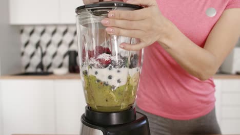 woman putting the ingredients in the blender and mixing them