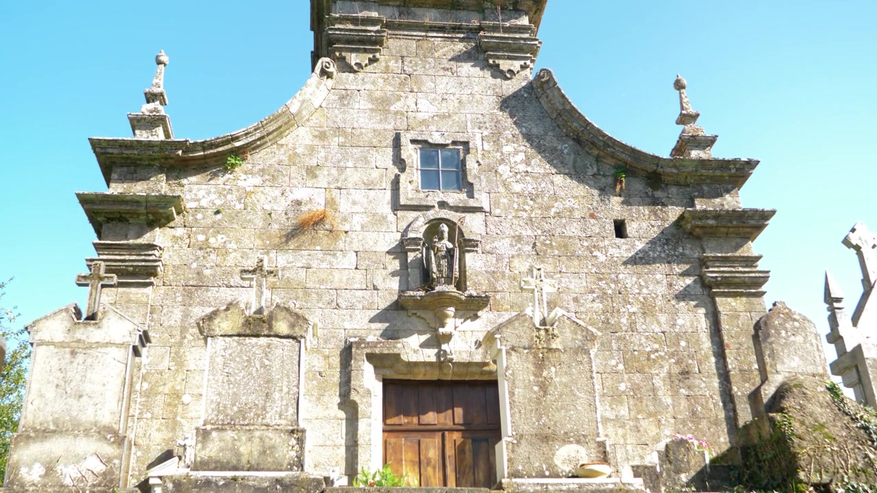 Facciata in pietra della chiesa di San Martiño a Porqueira, Ourense, Galizia, Spagna sotto un cielo sereno.