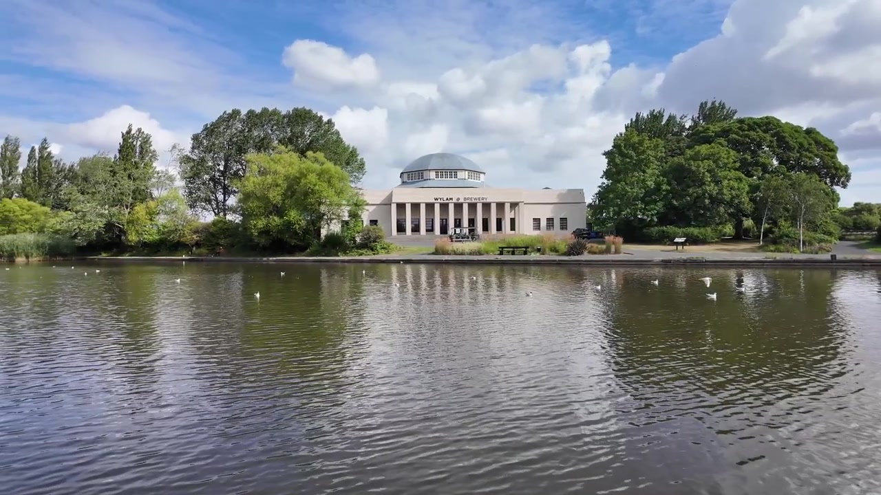 Wylam Brewery Palace of Arts attraverso il lago dell'Exhibition Park a Newcastle upon Tyne, Inghilterra