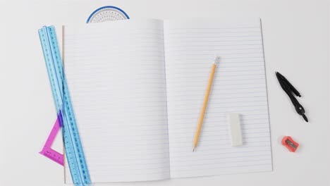 overhead view of open notebook with school stationery on grey background, in slow motion