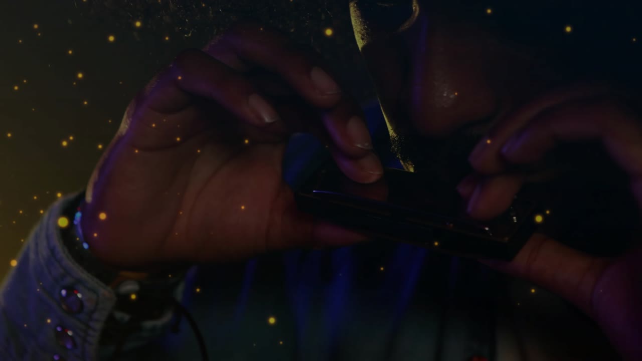 Seorang pria memegang harmonika di mulutnya dan bermain musik sementara sebatang rokok diletakkan dan partikel melayang.