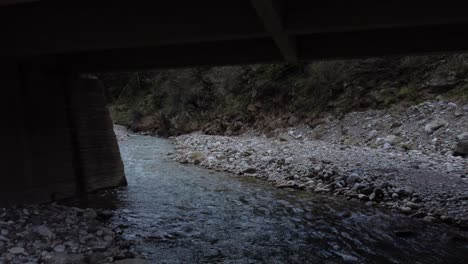 flying under a bridge in an ominous landscape with a river | 4k