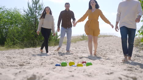 Side-view-of-caucasian-young-woman-throwing-a-petanque-ball-on-the-beach-on-a-sunny-day