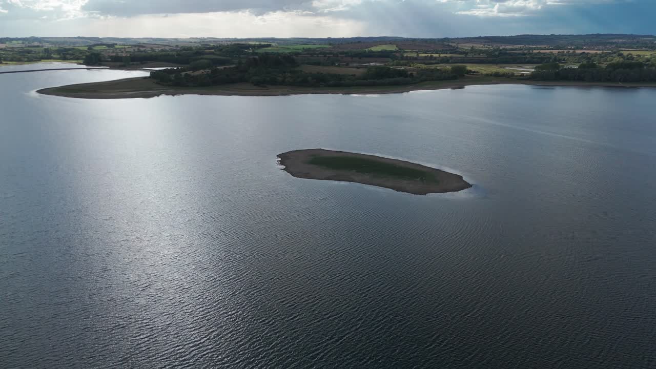 Isolated island in Rutland Water, UK amid serene lake and sky views