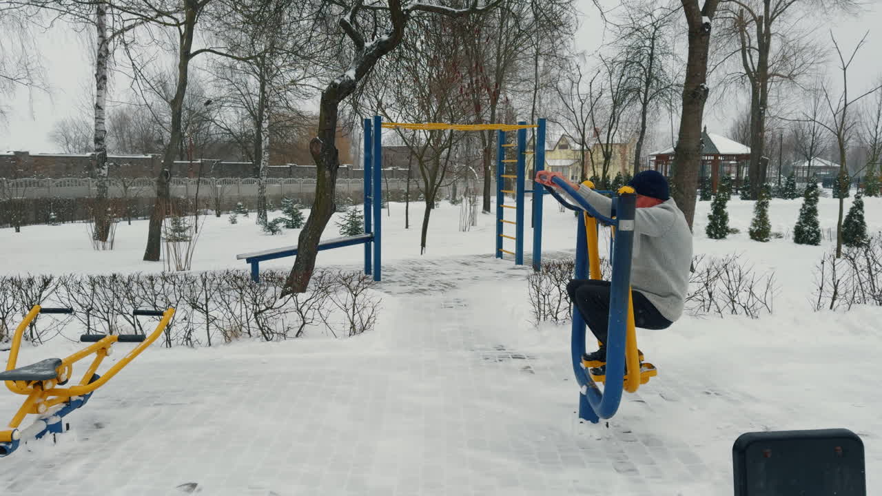 Active old man practicing on the sport simulator. Healthy lifestyle for aged male in winter outdoors.