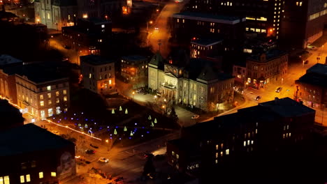 Cars-Driving-In-The-Street-Of-Sherbrooke-City-With-Christmas-Trees-And-Decorations-In-The-Park-At-Night