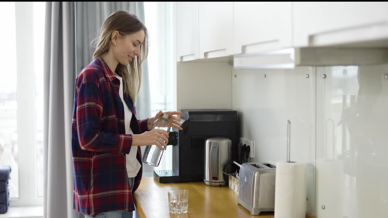mujer vertiendo agua fresca en un vaso, bebiendo agua en la cocina doméstica